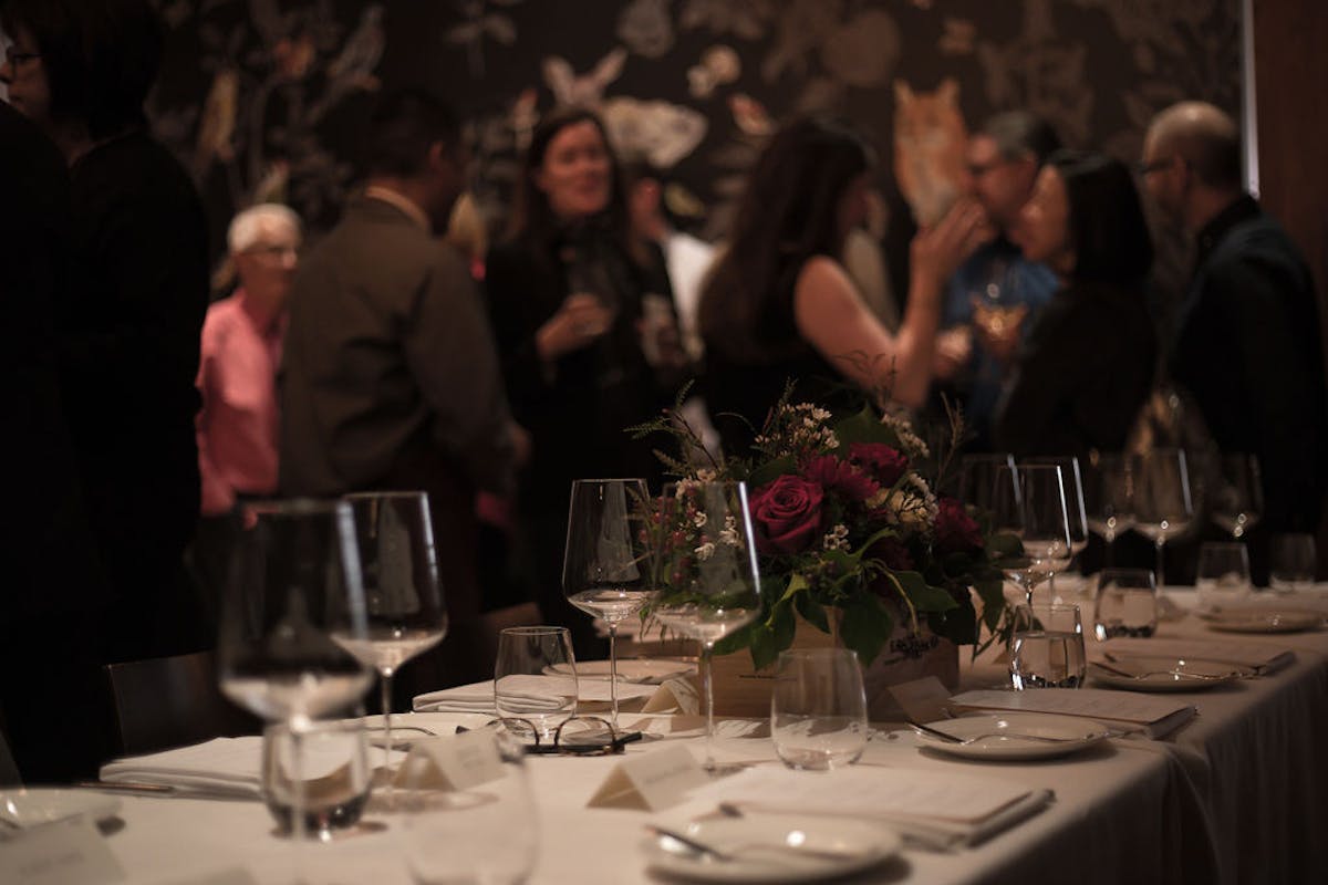 a close up of cups of wine on a table and a group of people on the background